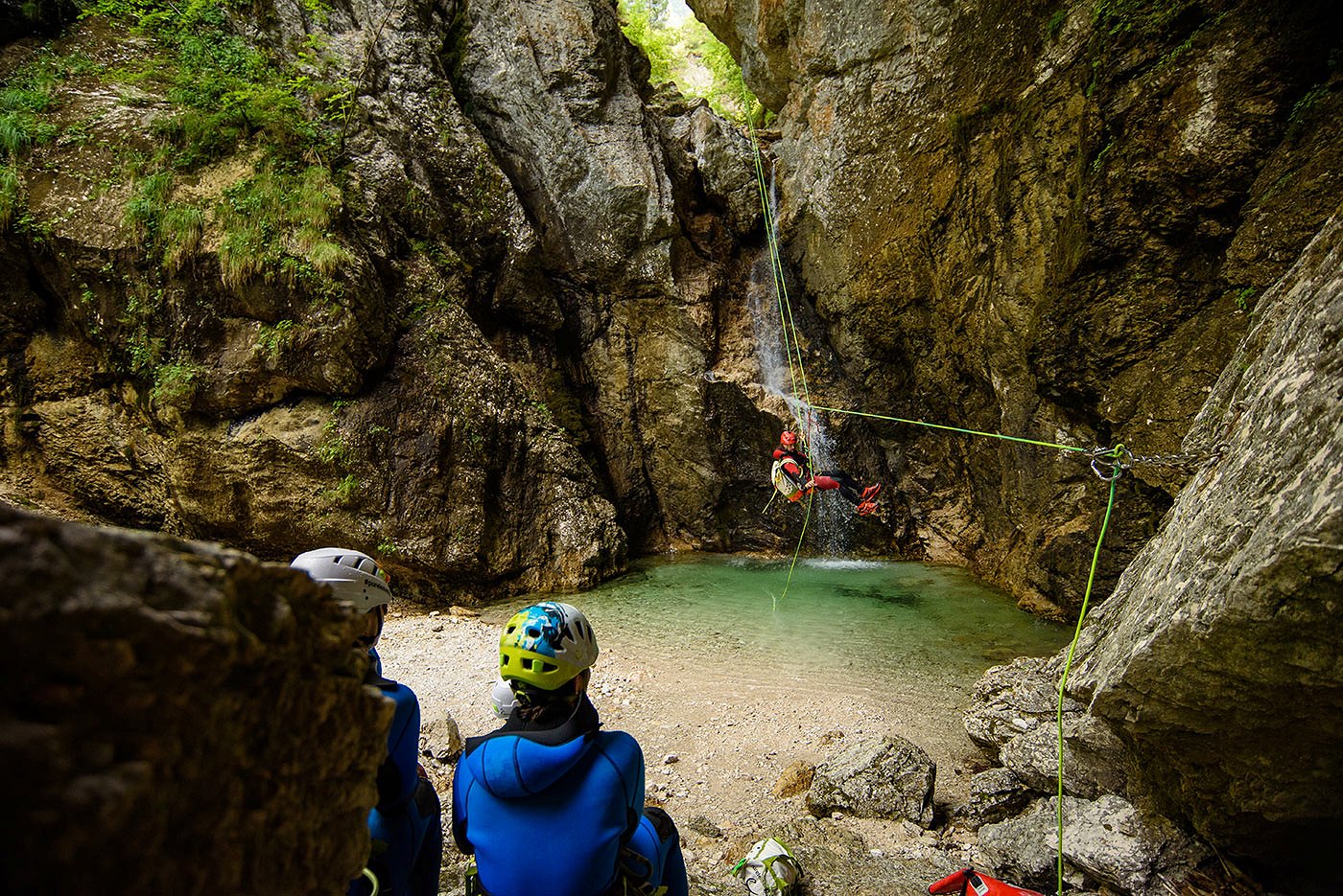 Canyonista scende dalla cascata con la corda dove un gruppo lo aspetta