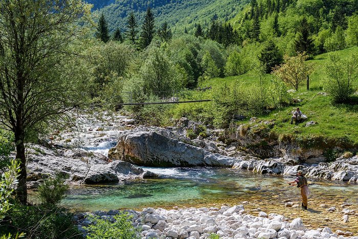 Fliegenfischer an einem grünen Pool unter einer Hängebrücke