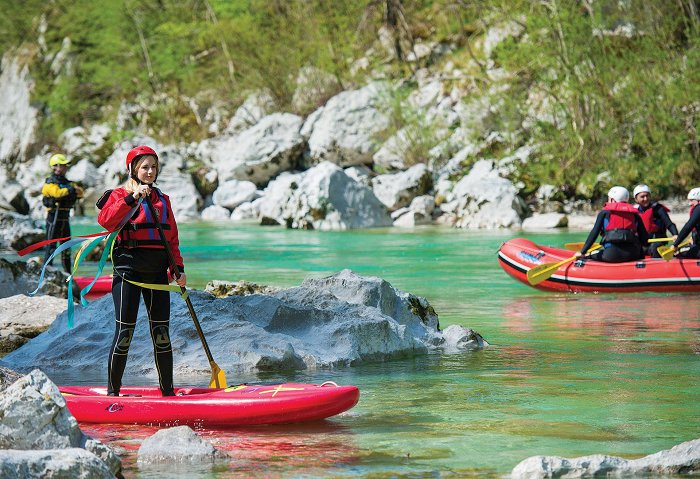 Ein Mädchen in voller Ausrüstung auf dem SUP am smaragdgrünen Fluss Soča