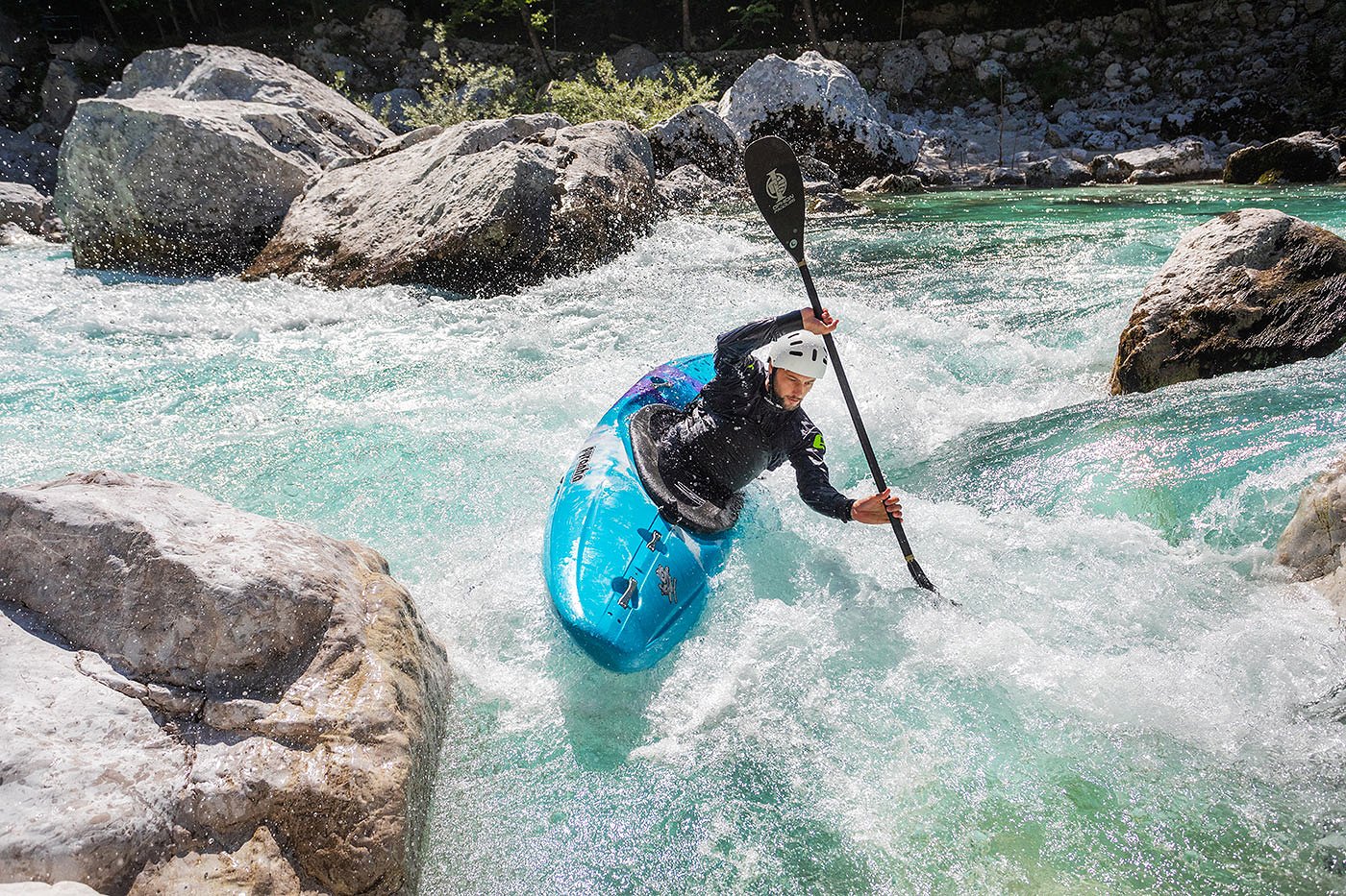 Der Kajakfahrer verwandelt sich in eine Gegenströmung auf dem smaragdgrünen Fluss Soča