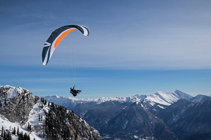 The paraglider descends into the snow-covered Bovec basin