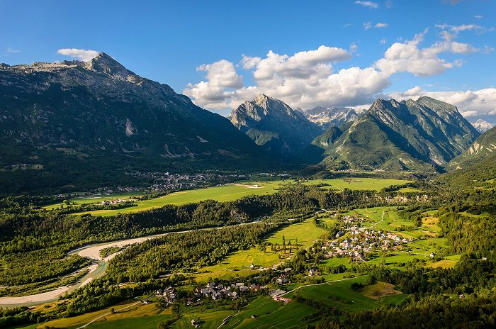 Razgled na mesto Bovec in vas Čezsoča, med katerima teče reka Soča, v ozadju lokalni hribi