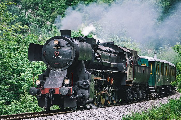 Eine schwarze Dampflokomotive zieht grüne Wagen