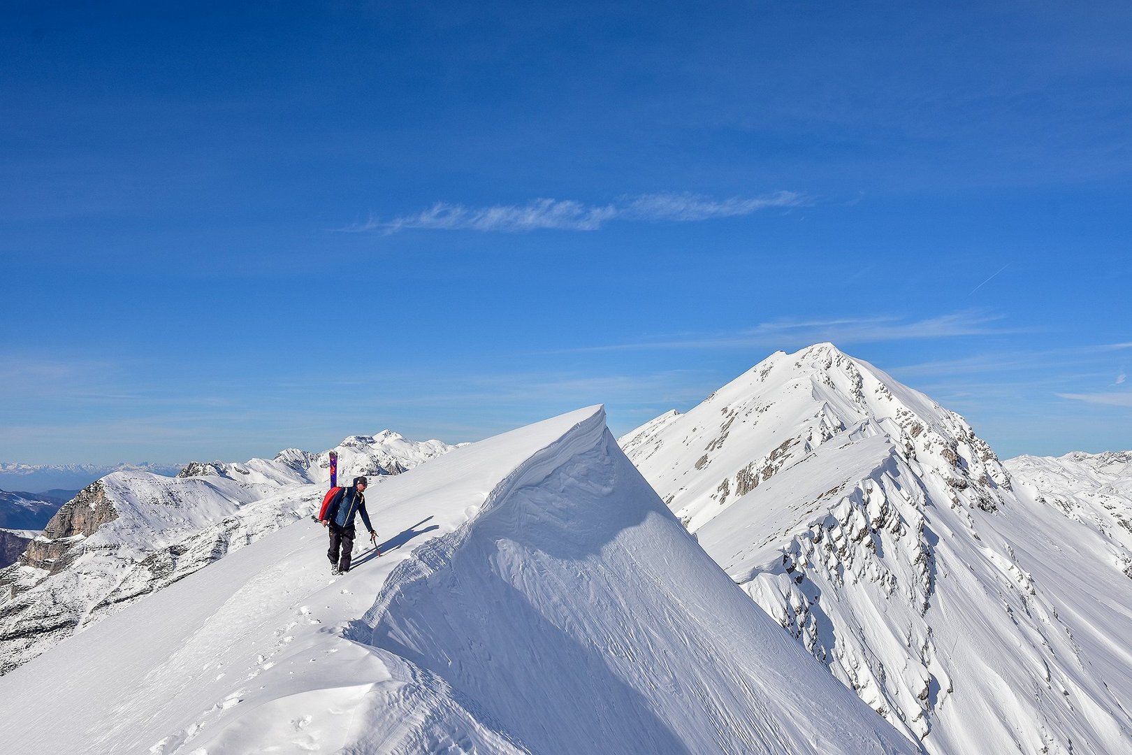 Lo sciatore alpinista gode della vista dalla cima di una montagna innevata
