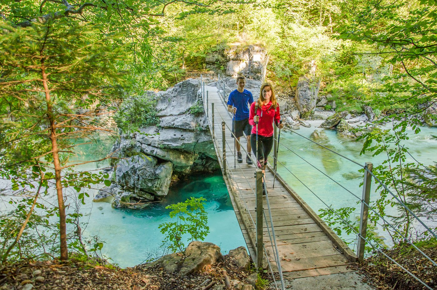Hikers cross the footbridge across the Soča River