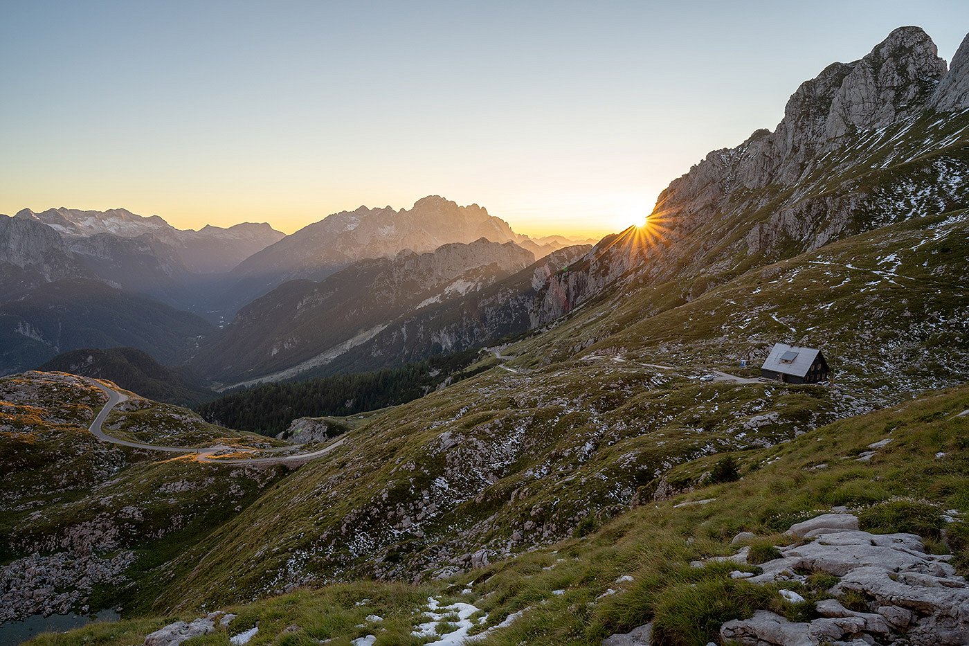 the sun sets behind the mountains surrounding the Mangart hut