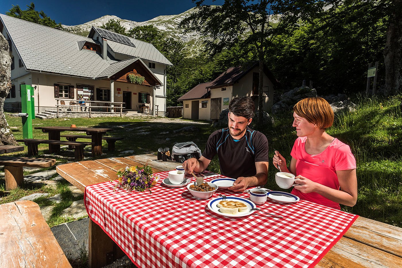 La coppia sulla panchina davanti al rifugio gusta ottimi piatti di montagna