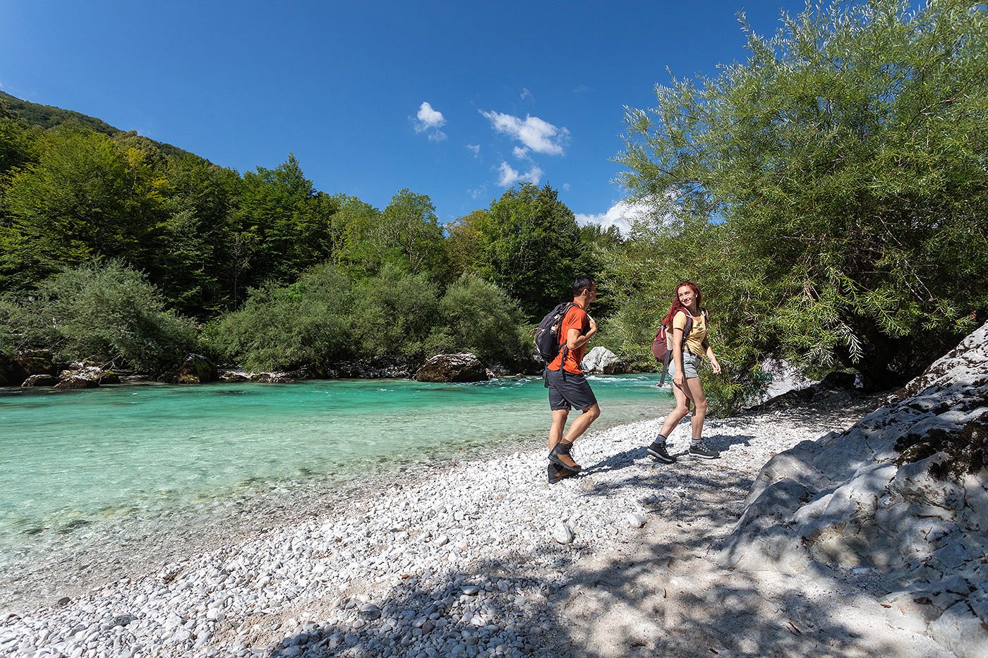 Die Wanderer wandern am sandigen Ufer des Flusses Soča entlang