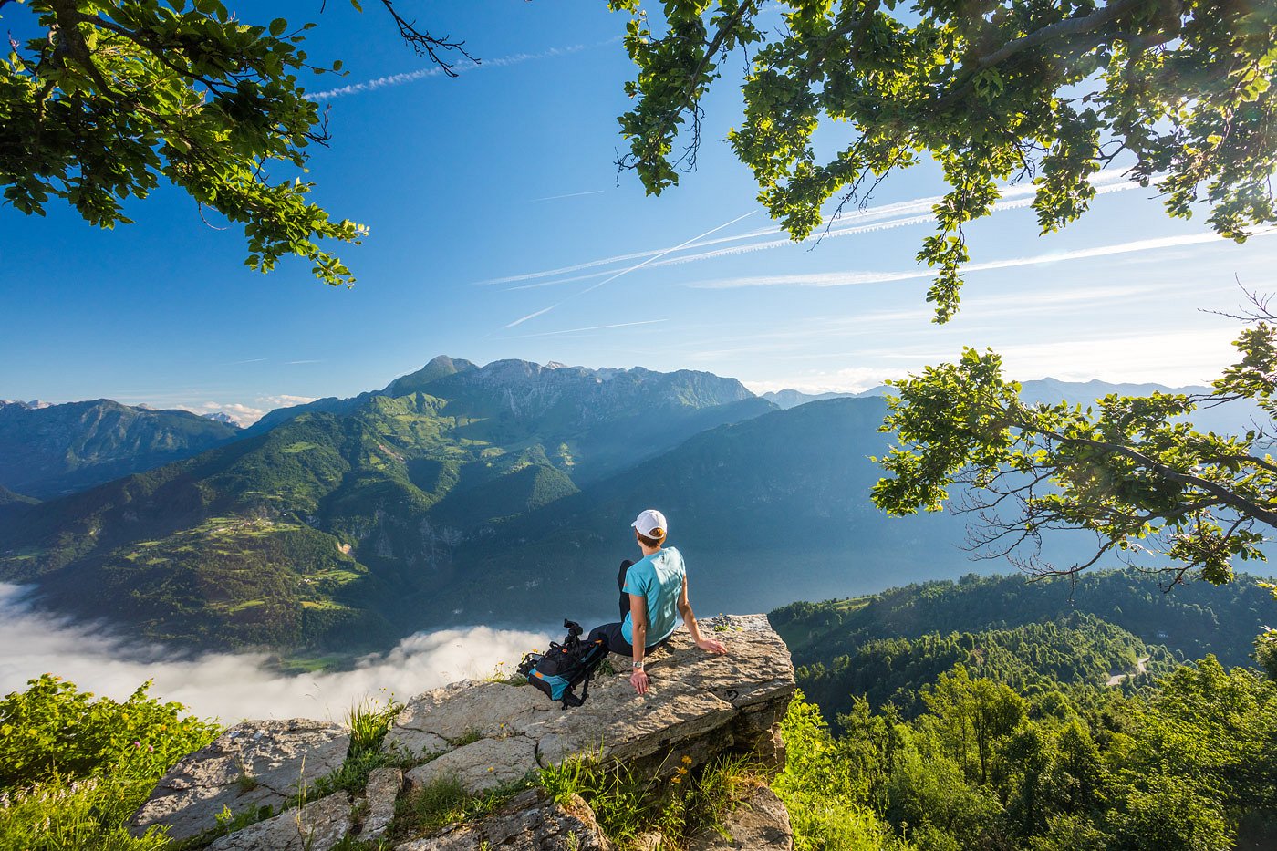 The hiker rests on a rock with a view of the Soča Valley