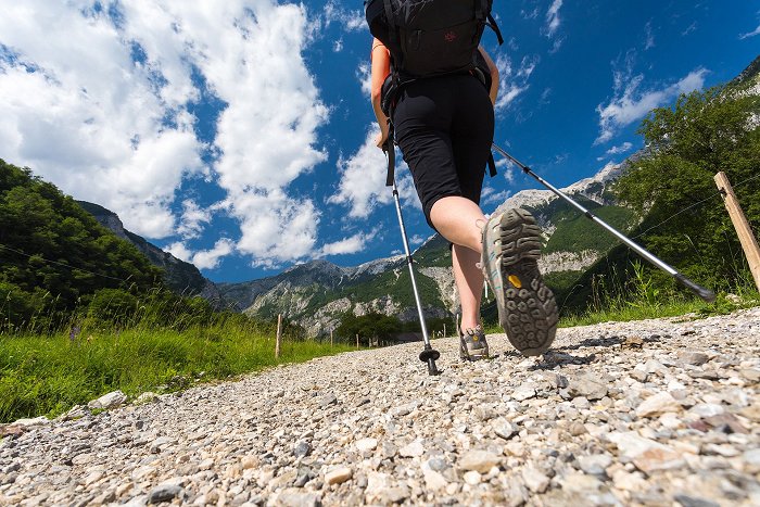 L\'escursionista parte per un\'escursione con scarpe e bastoncini da trekking.