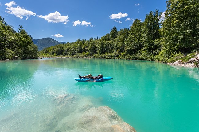 Il canoista si sdraia su un kayak e si rilassa in una parte tranquilla dell'Isonzo alla fine della discesa lungo le rapide