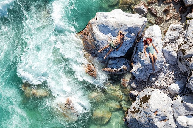 Das Paar im Badeanzug liegt auf den Felsen an den Stromschnellen der Soča.