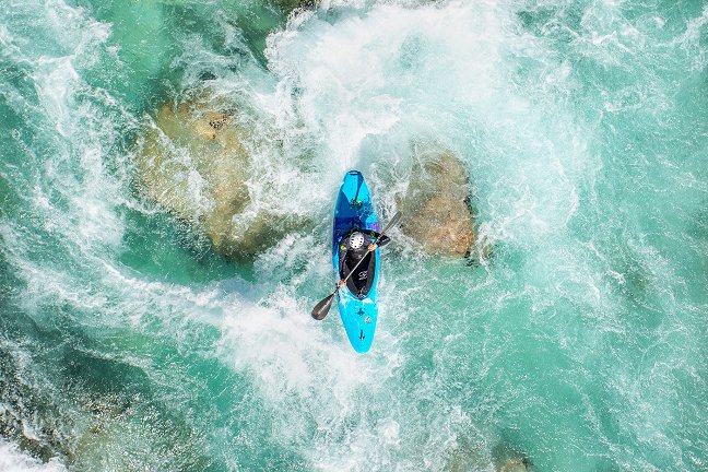 The kayaker descends the emerald rapids of the Soča River.