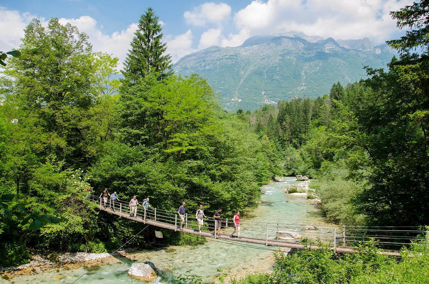 Pohodniki prečkajo leseno brv čer reko Koritnico
