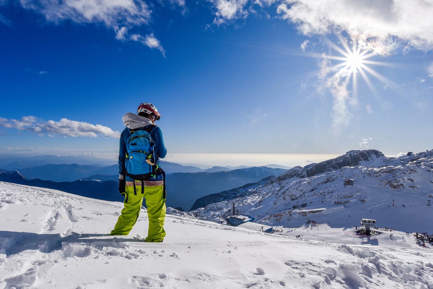 The skier enjoys the views of the valley from the ski slope bathed in sunshine.