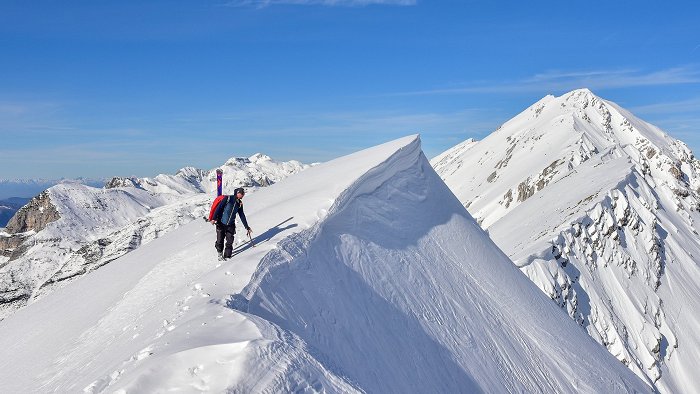 The touring skier enjoys the view at the top of a snowy mountain